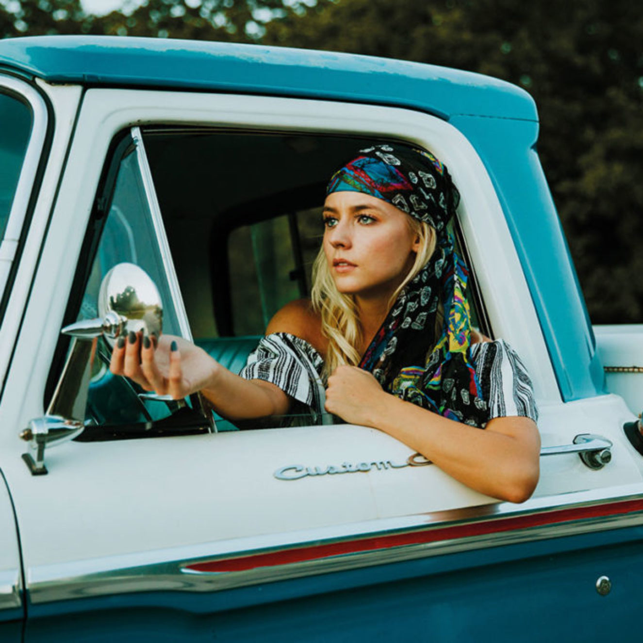 Woman sitting in a vintage truck with a scenic background