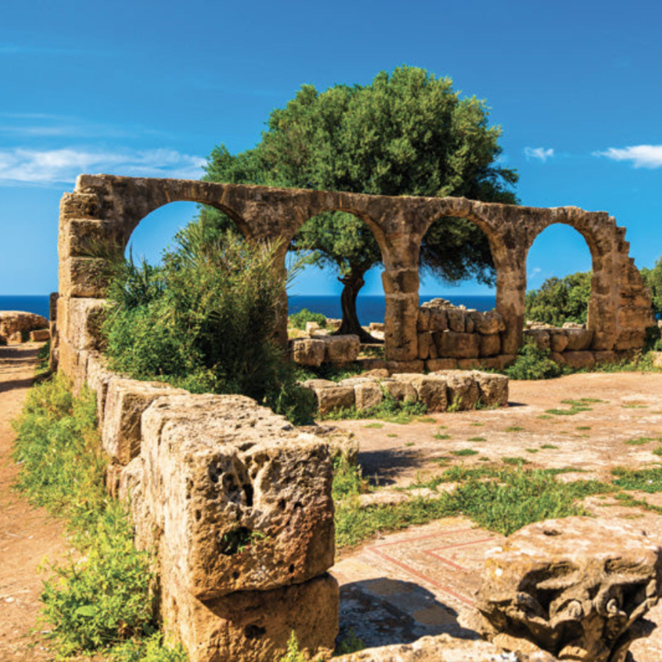 Ancient stone ruins with arches overlooking a coastal landscape.