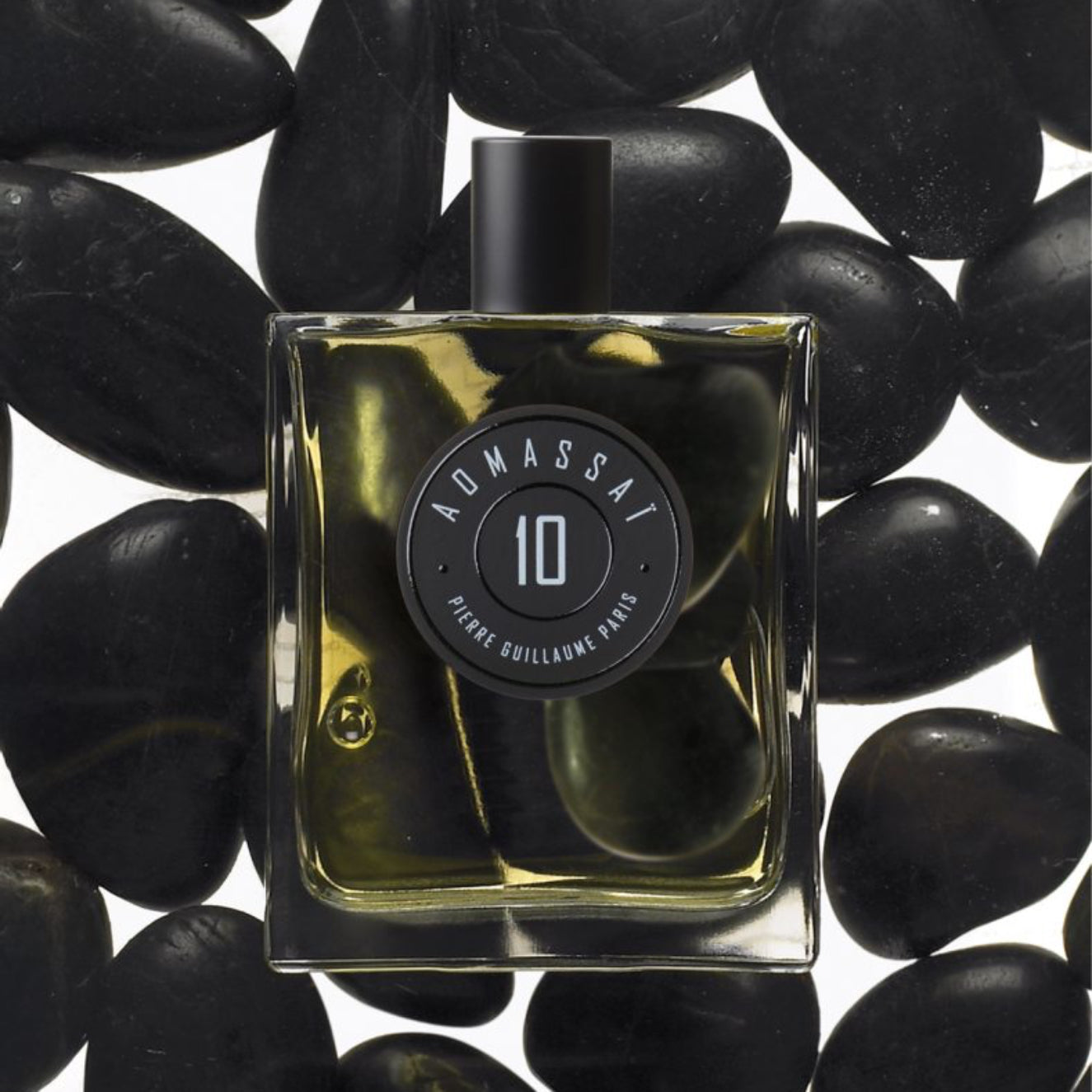 Perfume bottle labeled 'Admassal 10' on black stones