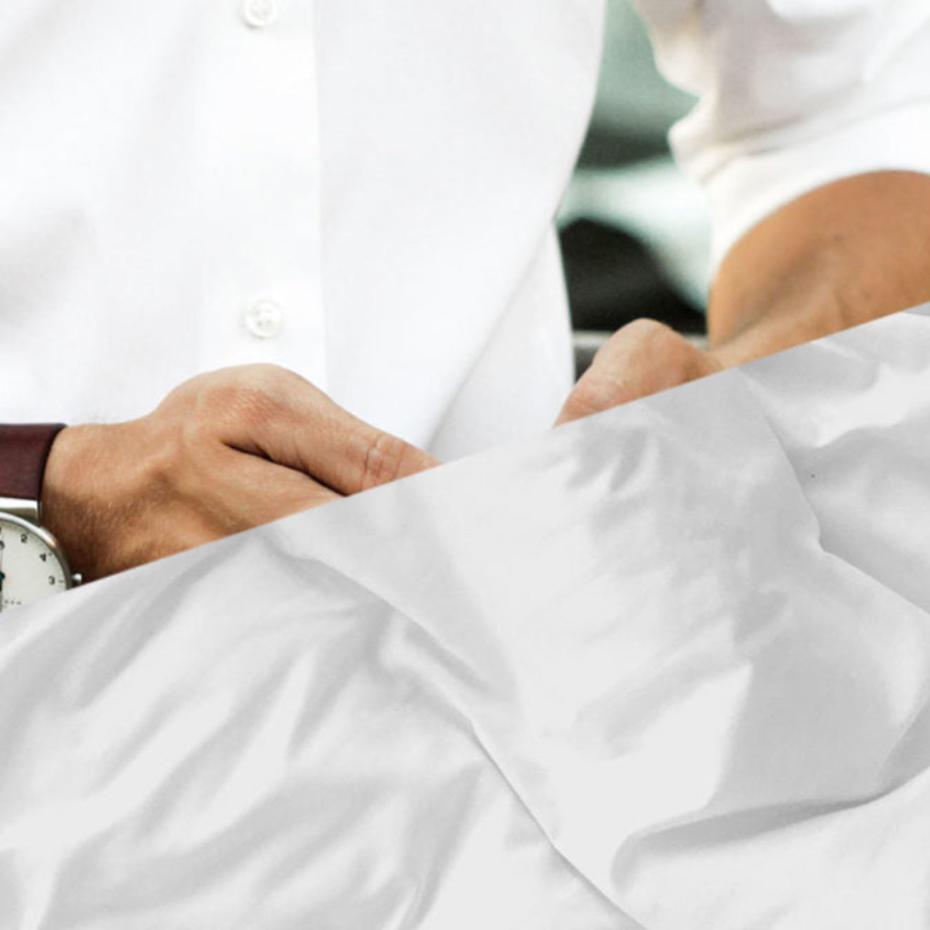 Person wearing a white coat with a watch on their wrist, lying down.